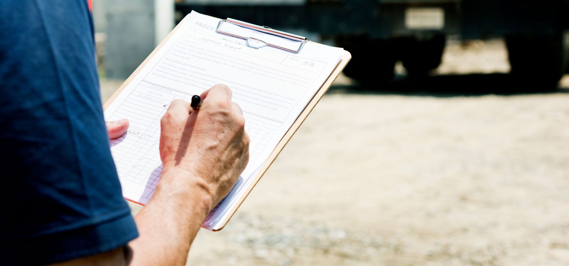 A man is writing on a clipboard with a pen.