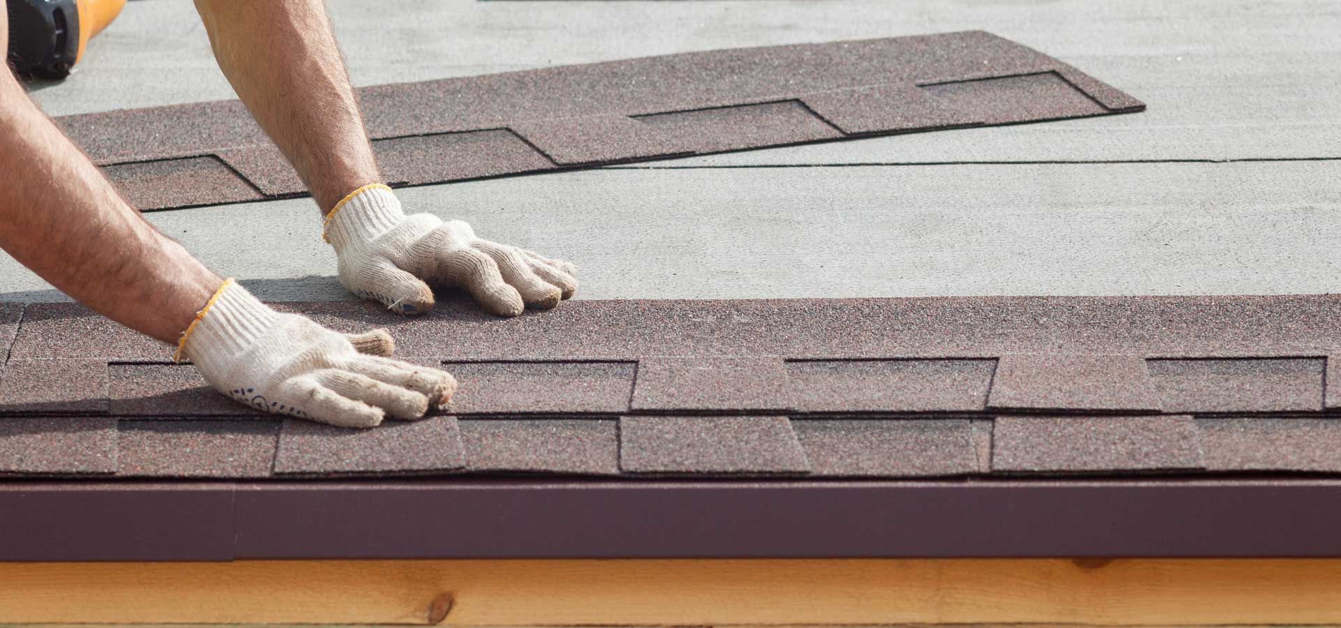 A man is installing shingles on a roof.