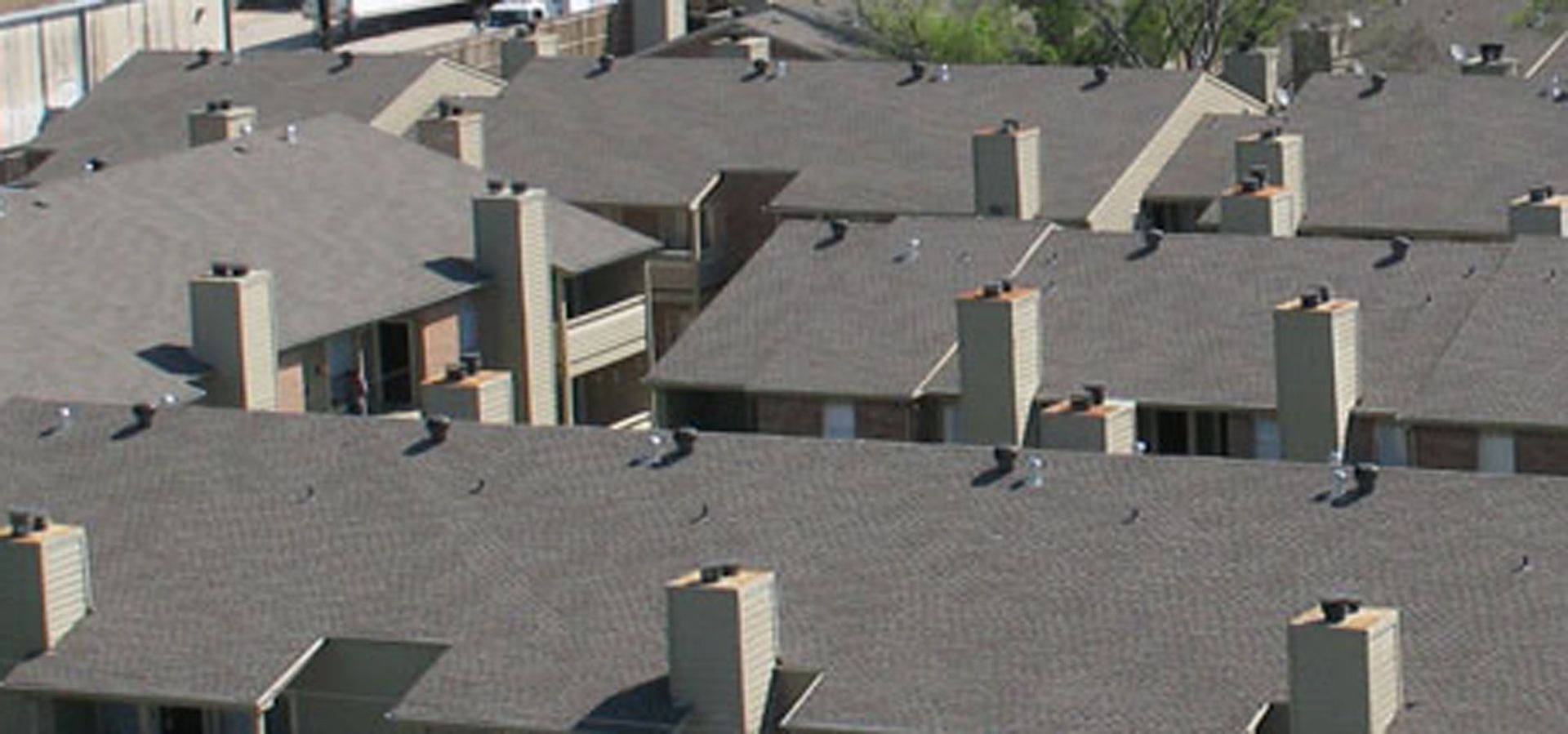 A row of apartment buildings with chimneys on the roofs