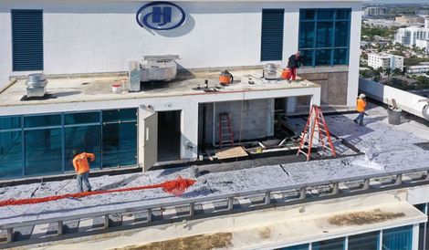 An aerial view of a building under construction with workers on the roof