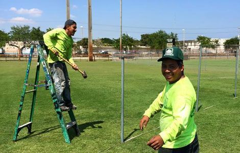 Two men are painting a fence in a field.