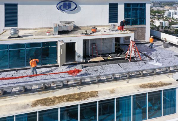 A group of construction workers are working on the roof of a building.