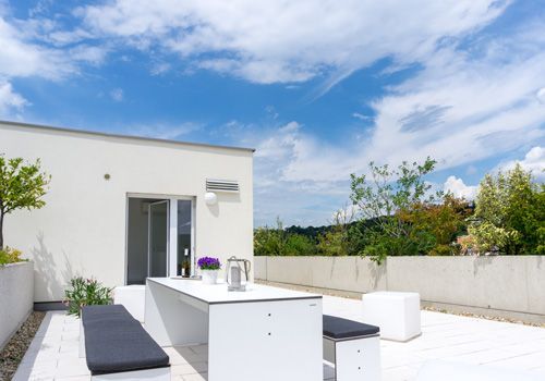 A white table and benches on a low slope roof-top patio.