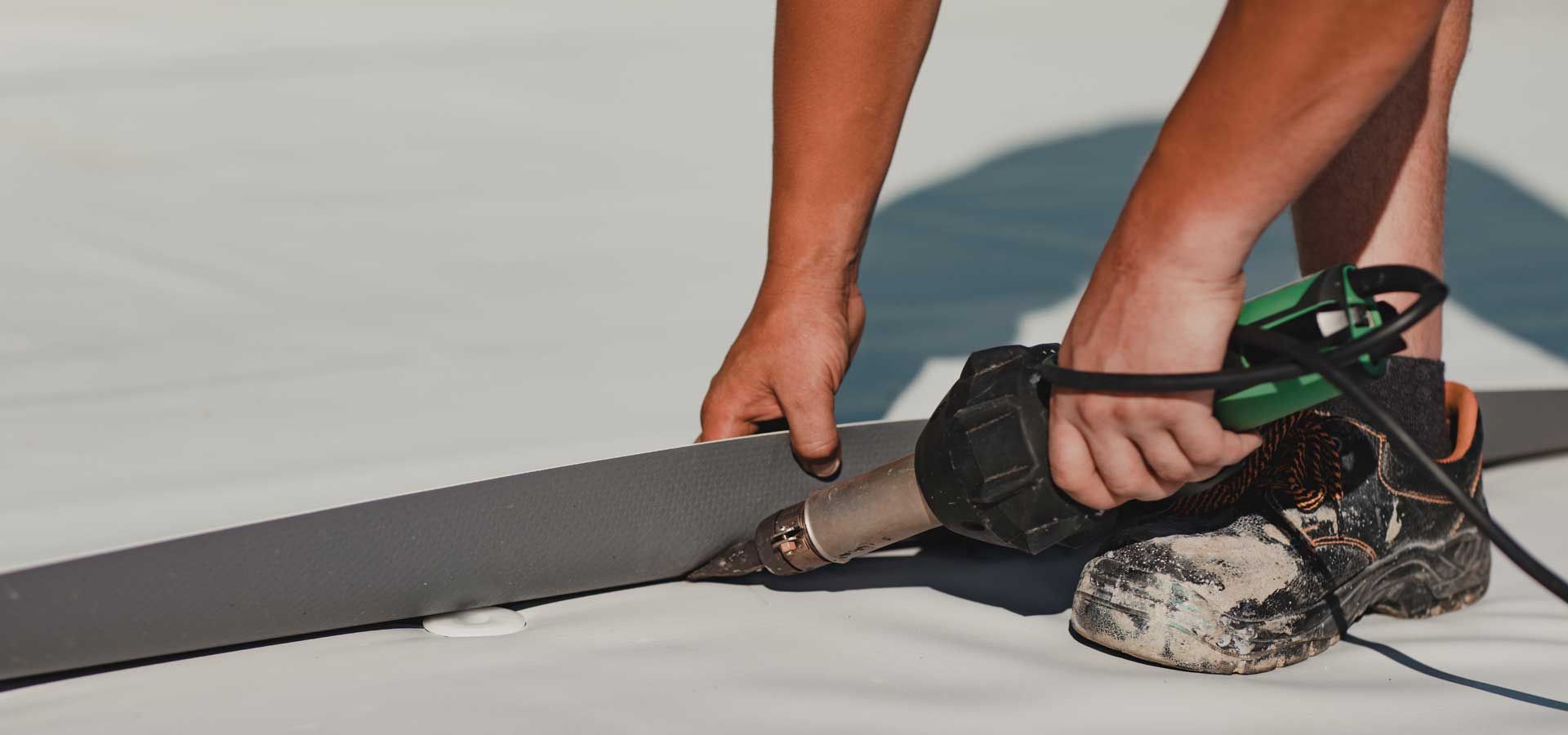 A person is working on a roof with a tool.