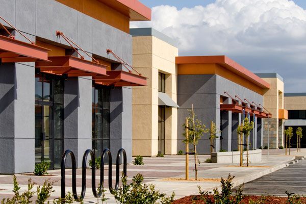 A row of retail buildings in a centre with a parking lot in front of them