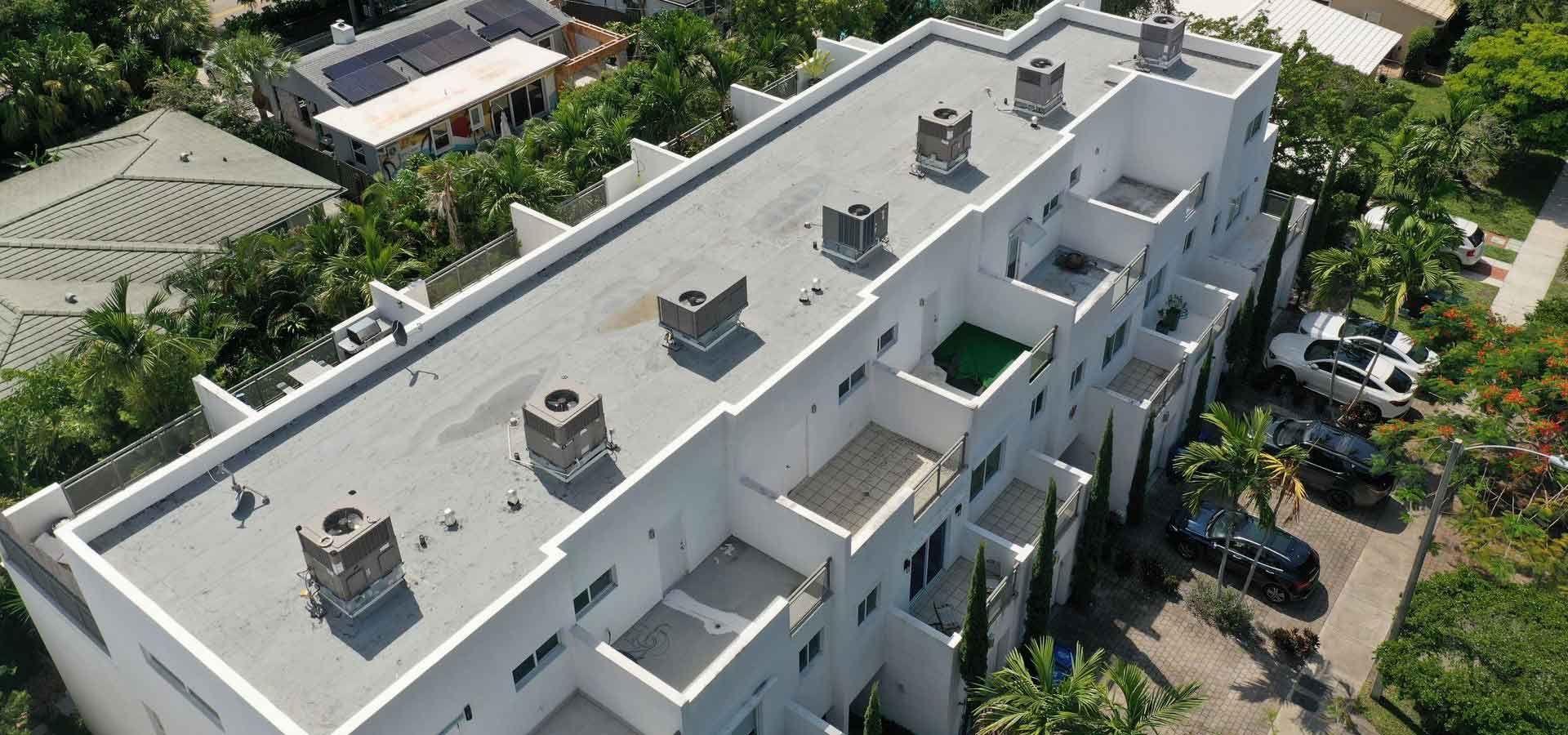 An aerial view of a large white apartment building surrounded by trees.