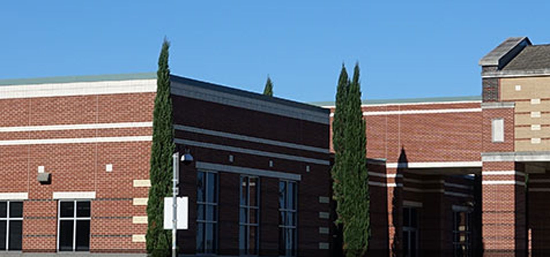 A large brick building with trees in front of it on a sunny day.