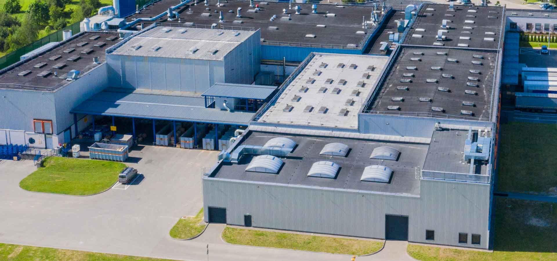 An aerial view of a large industrial building with a lot of windows on the roof.