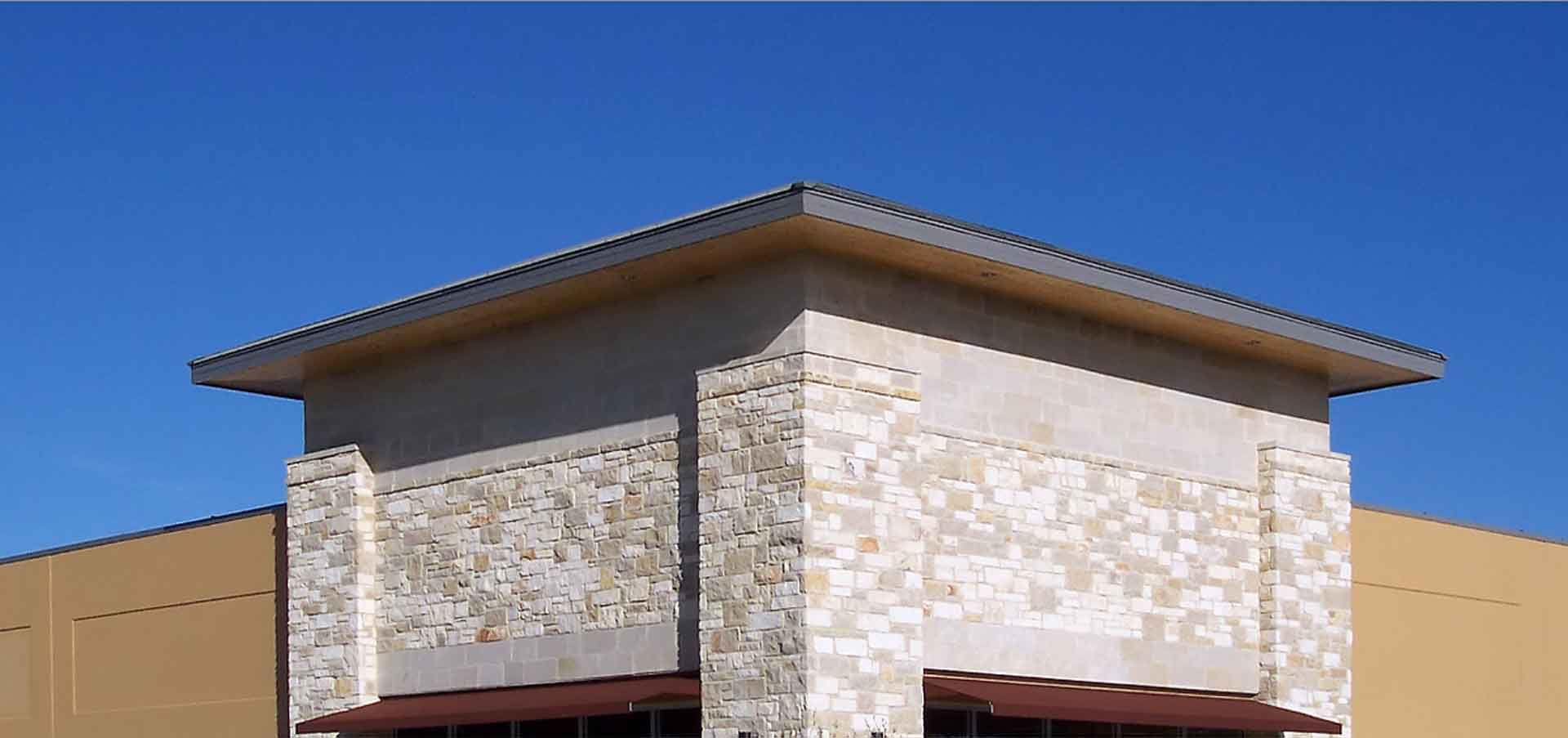 A building with a stone wall and a roof against a blue sky