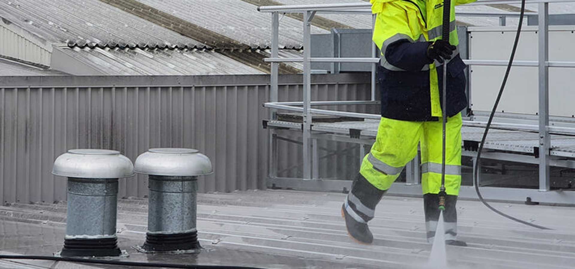 A man is coating a roof with a hose.