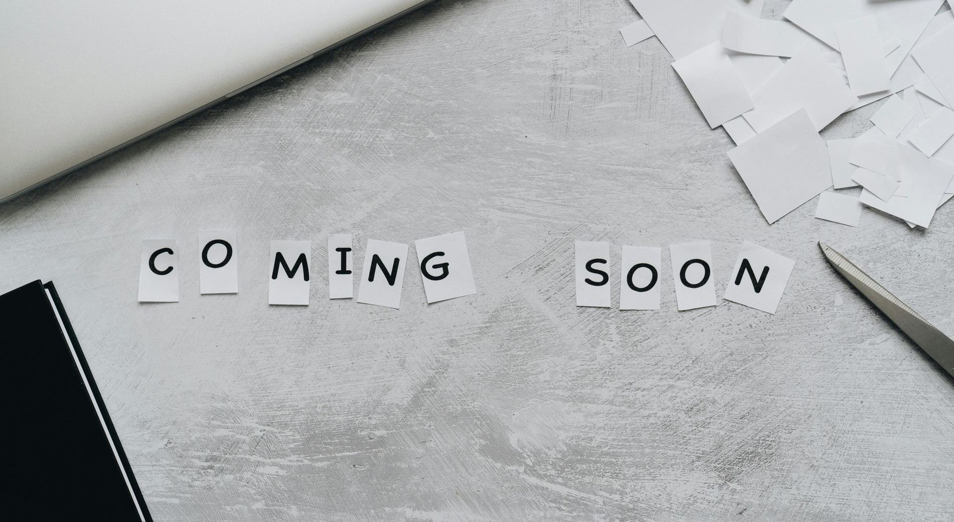 The word coming soon is written on a piece of paper on a table.