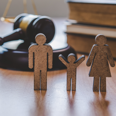 Wooden family figures with a gavel and books, representing legal proceedings.