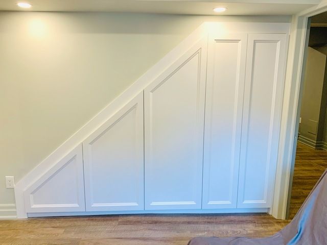 A room with a staircase and a closet underneath it.