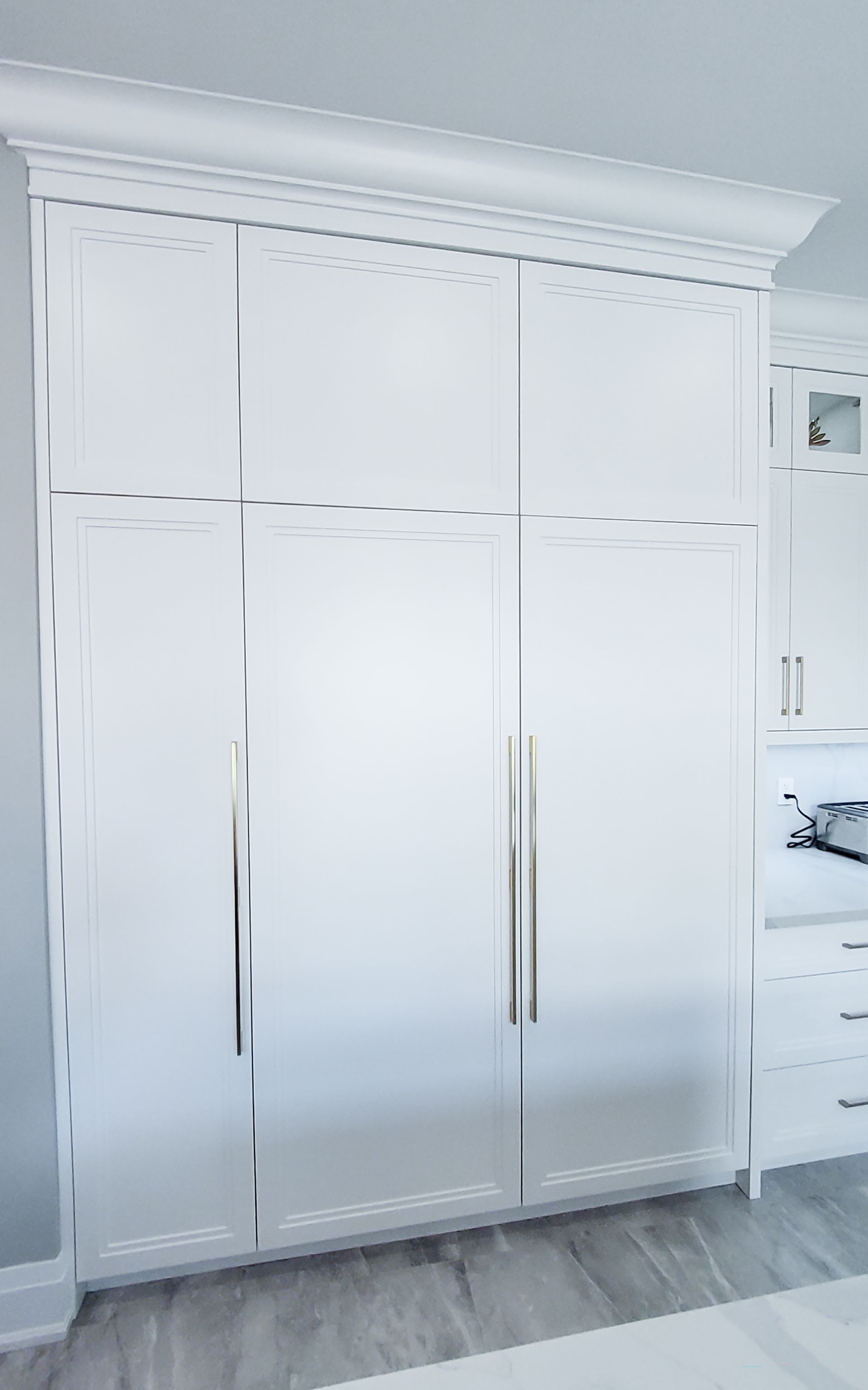 A kitchen with white cabinets and a stainless steel refrigerator freezer.