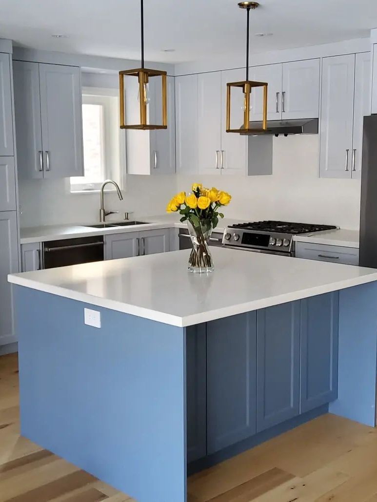 A kitchen with white cabinets , stainless steel appliances , and marble floors.