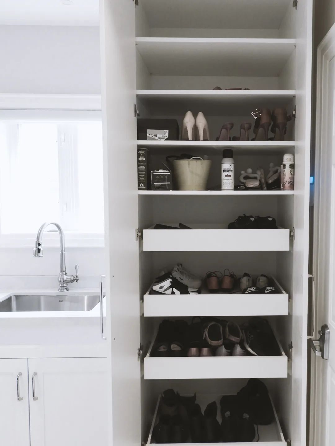 A kitchen with white cabinets and drawers filled with pots and pans.