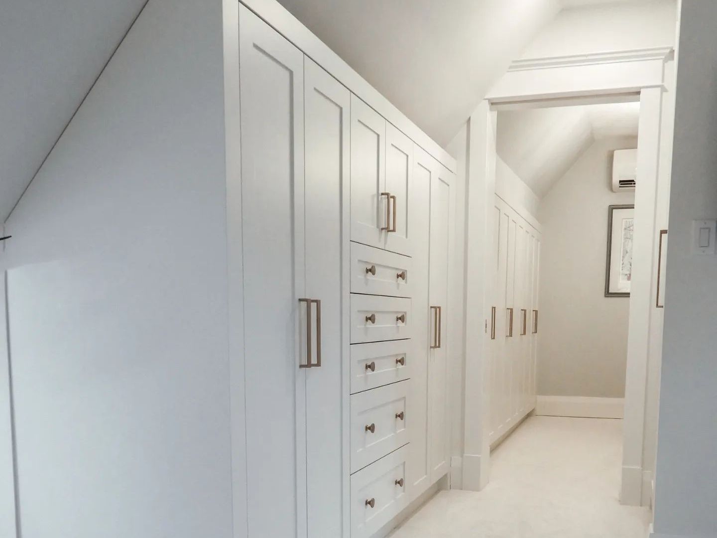 A hallway with lots of white cabinets and drawers