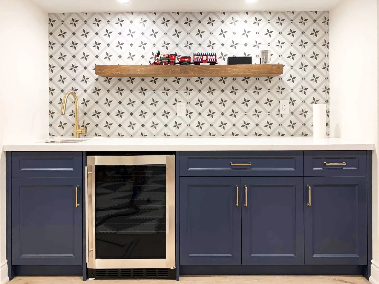 A kitchen with white cabinets and a black refrigerator.