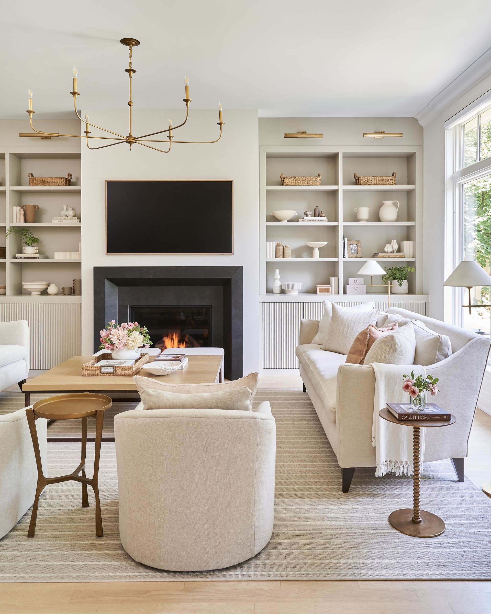 A living room with a fireplace, couch, chairs, table and television.