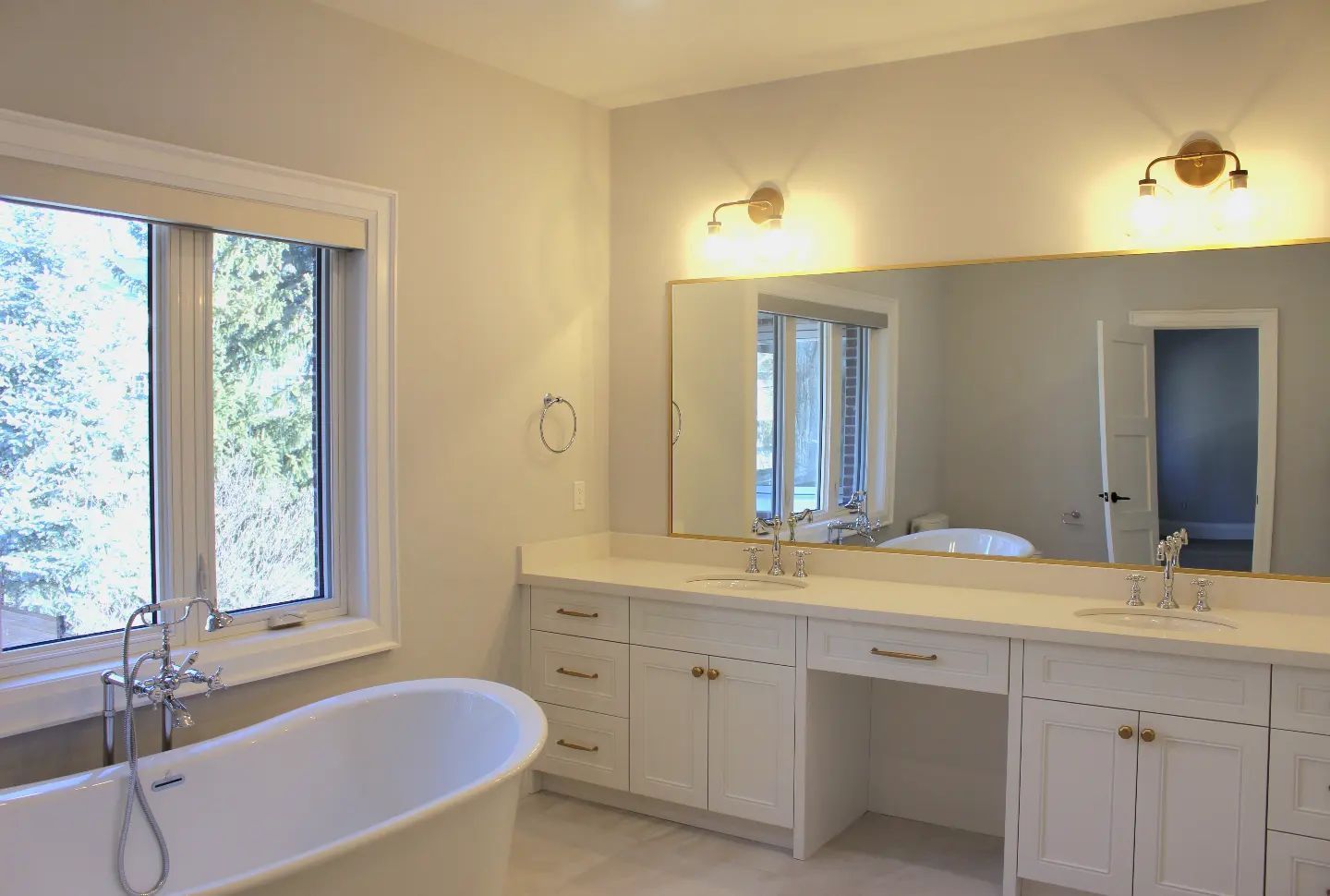 A bathroom with a tub , sinks , and a large mirror.