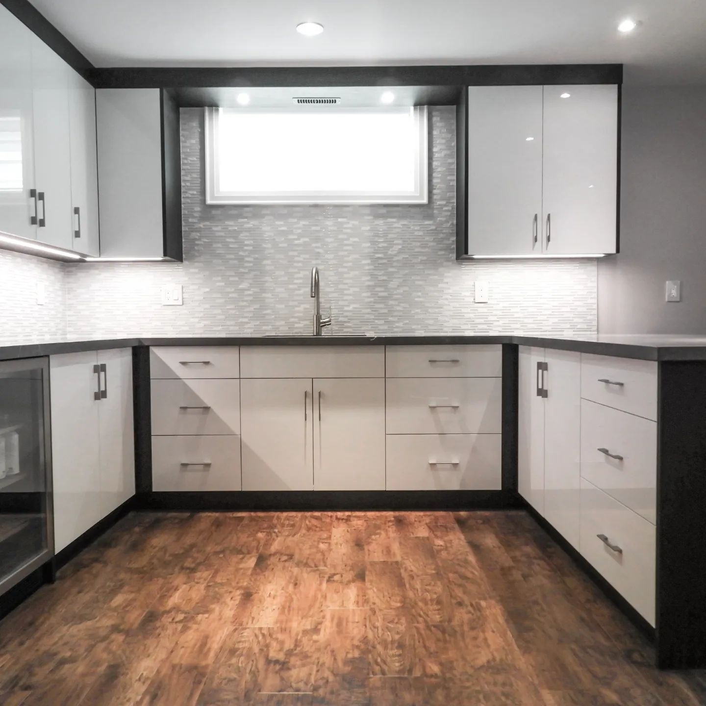 A kitchen with white cabinets and wooden floors