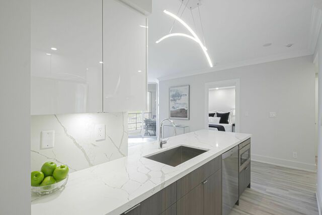 A kitchen with a sink and a bowl of apples on the counter.