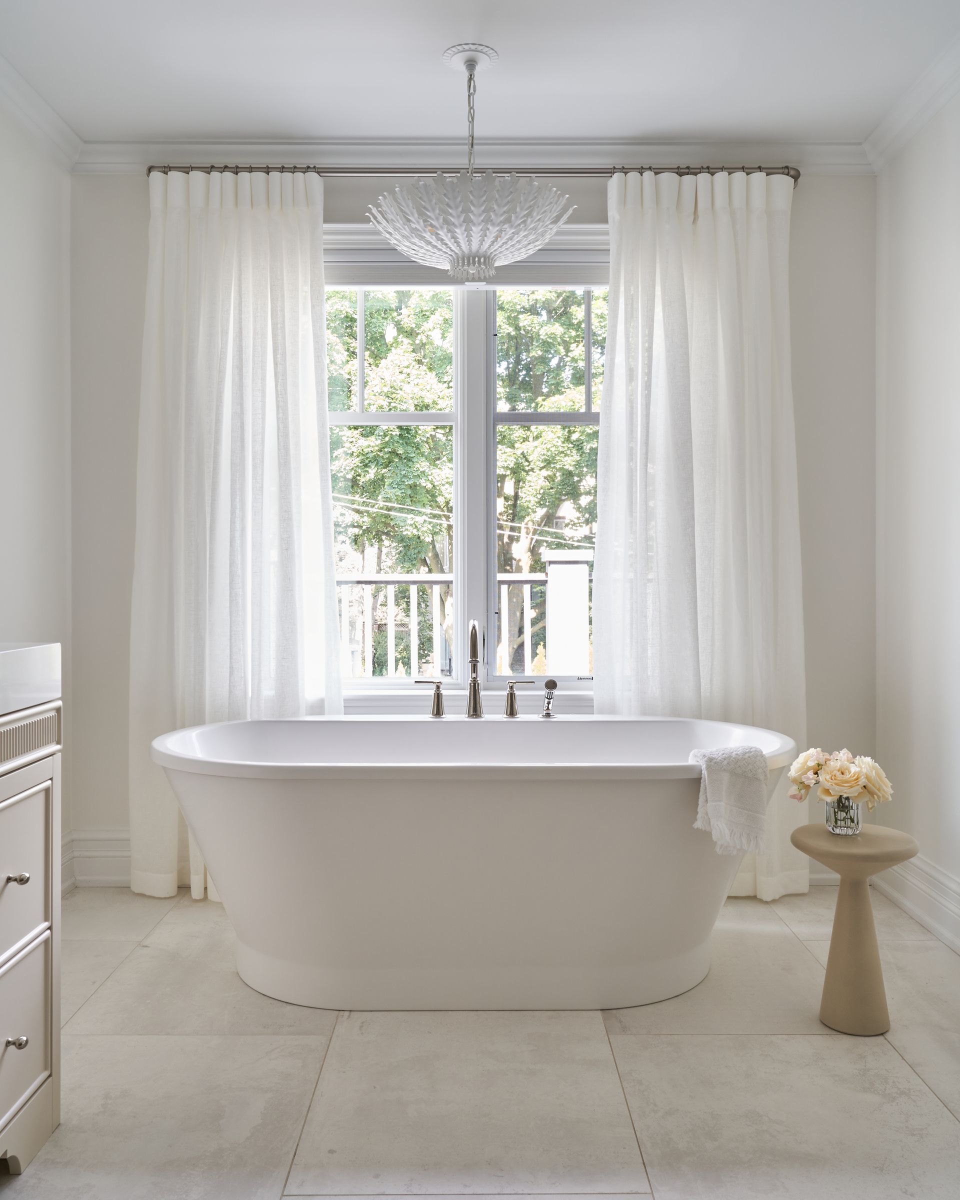 A bathroom with a tub and a window with white curtains.