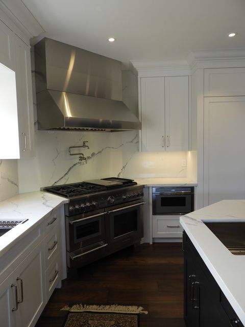 A kitchen with white cabinets and a black refrigerator.