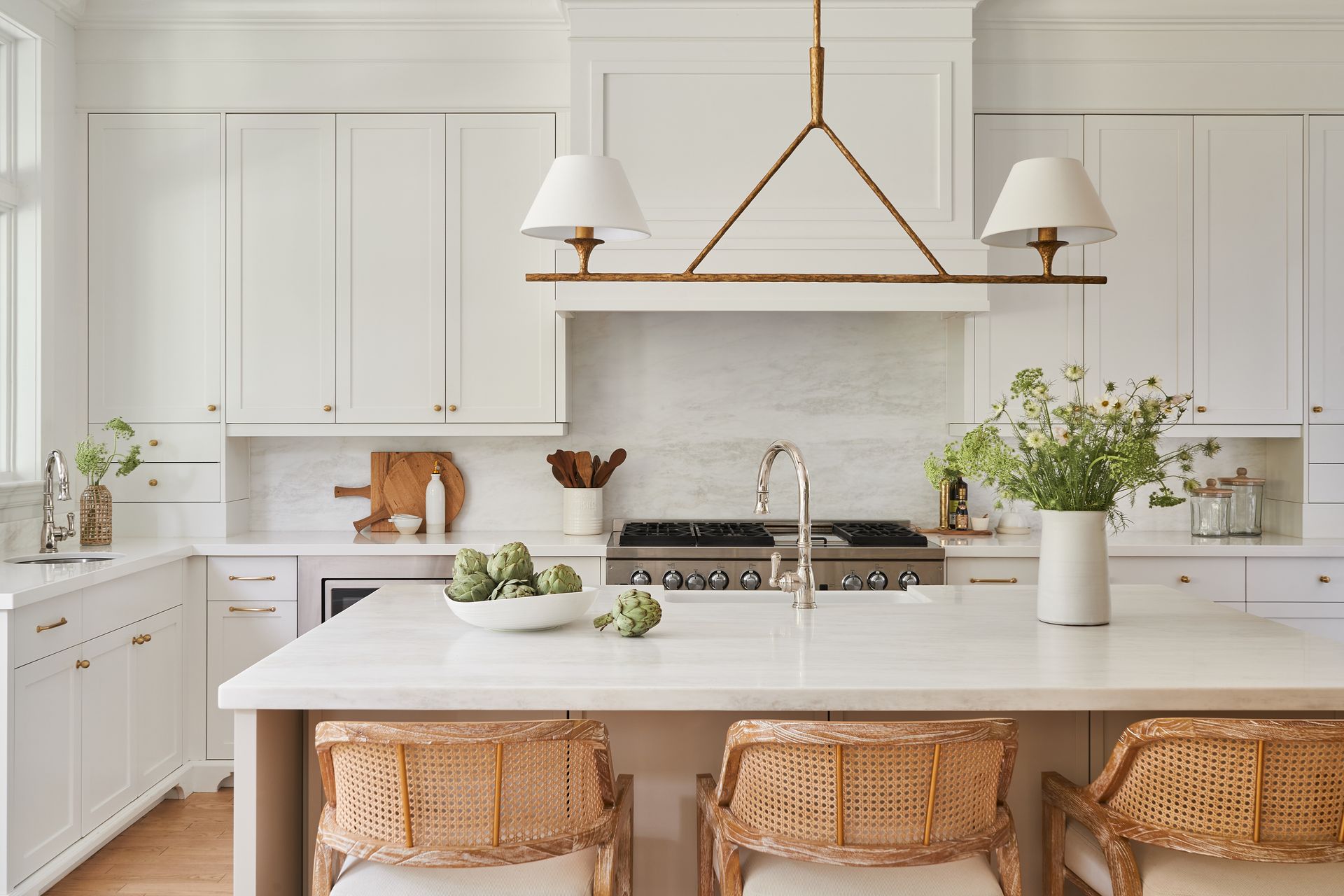 A kitchen with white cabinets and a large island with wicker chairs.