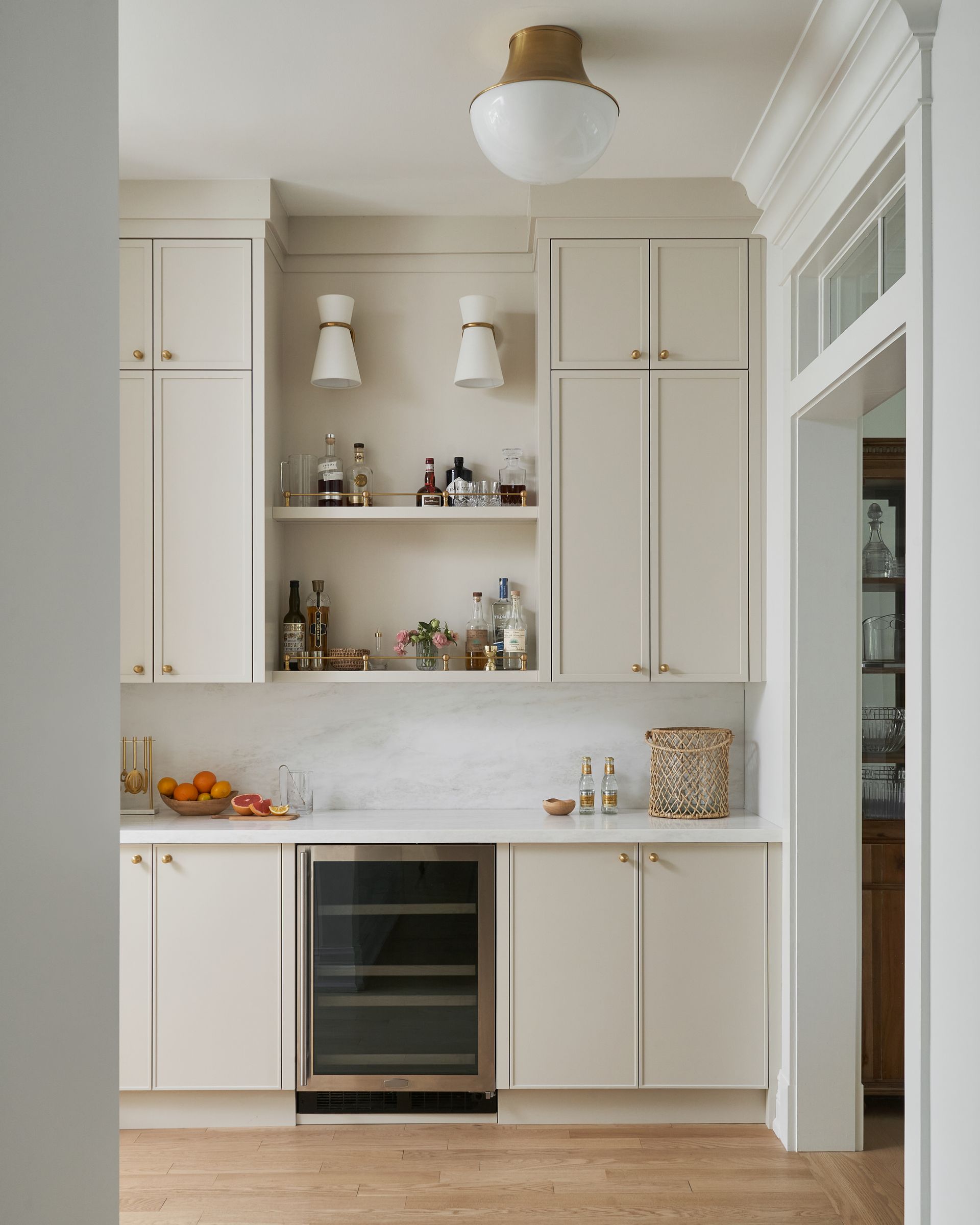 A kitchen with white cabinets and a wine cooler