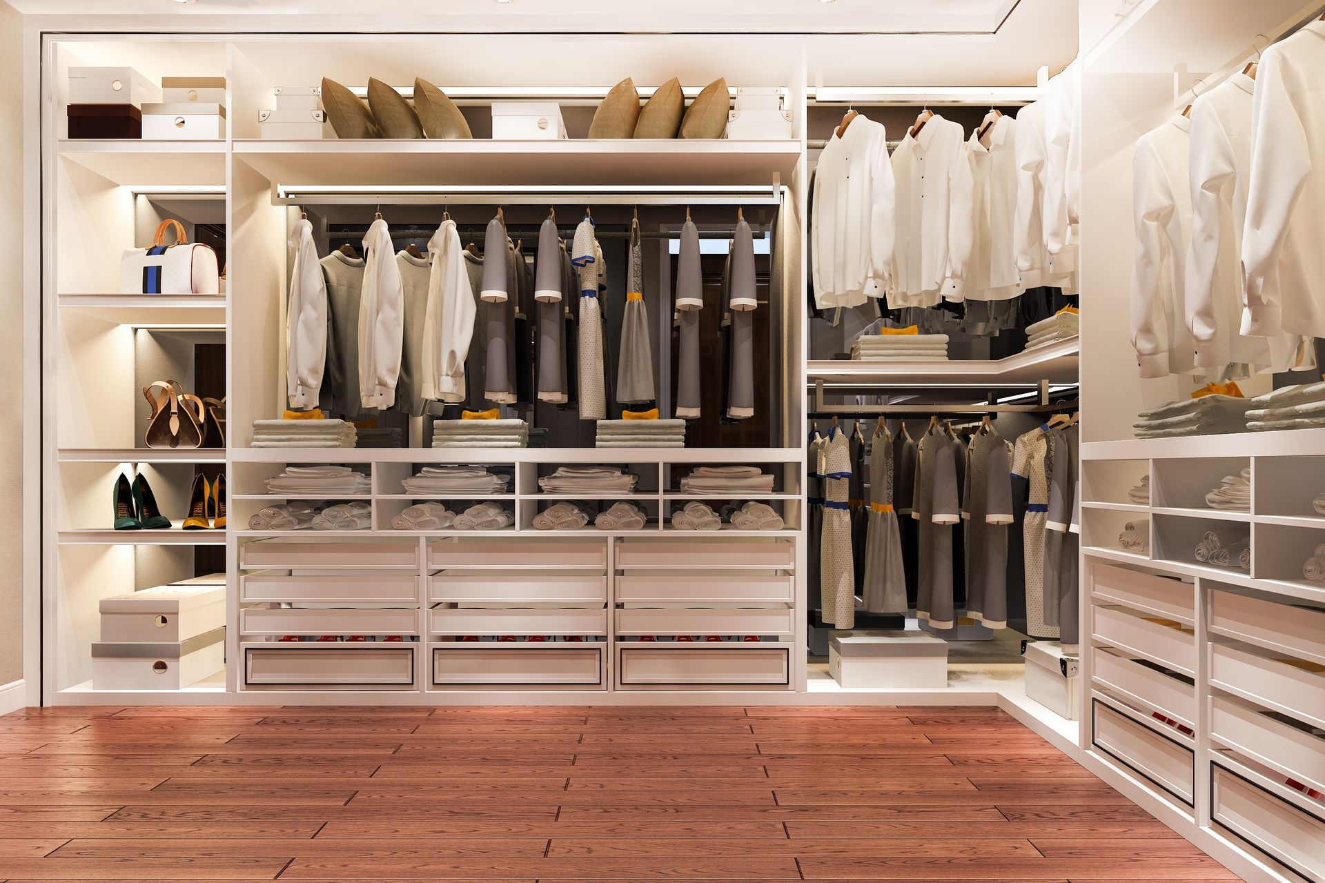 A luxurious, bright white walk-in closet with clothes racks, drawers, and shelving; wood flooring.