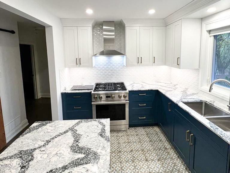 A kitchen with blue cabinets , white cabinets , a stove and a sink.