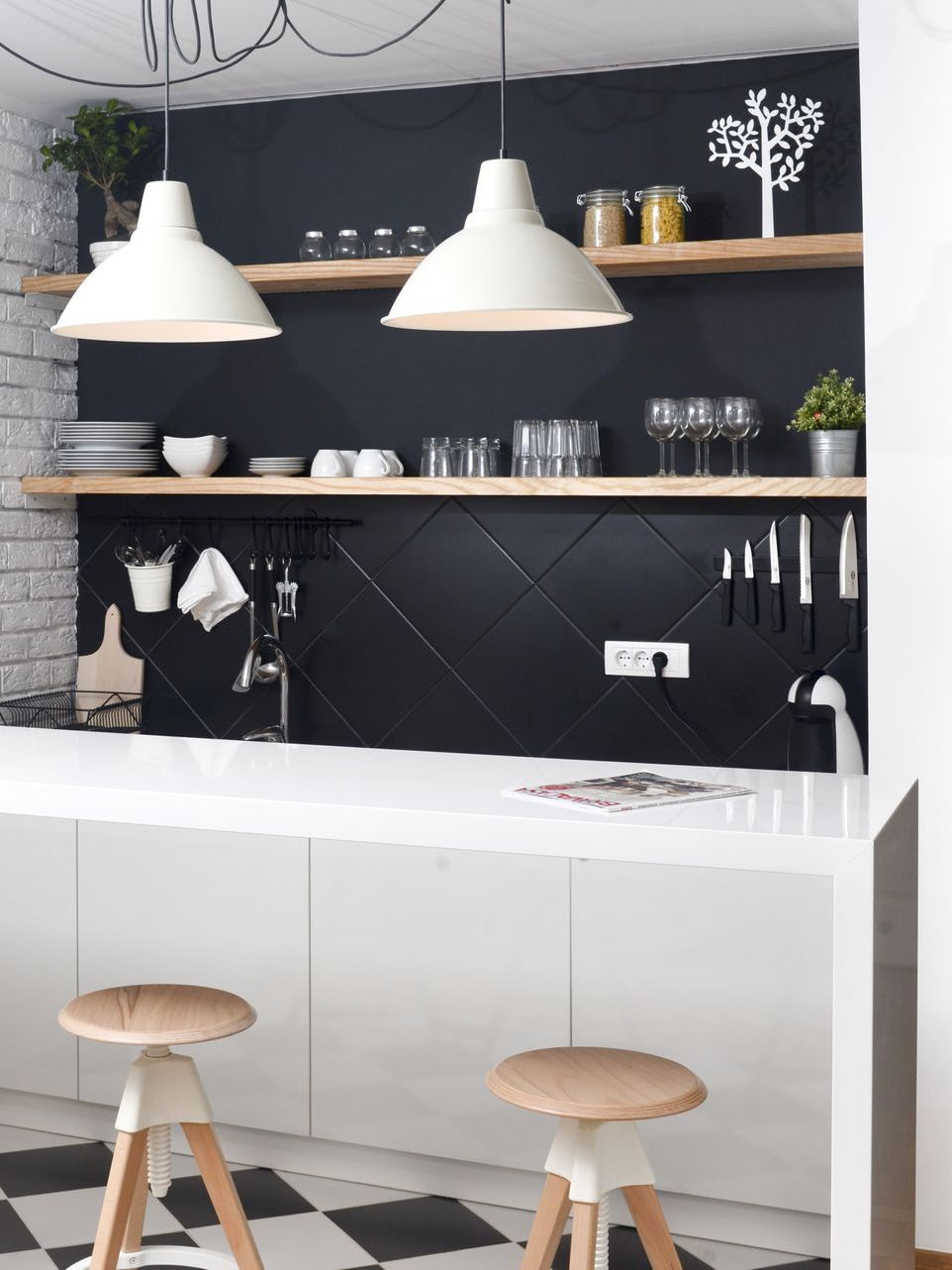 Modern kitchen with white island, black diamond-patterned backsplash, wooden shelves, and white pendant lights.