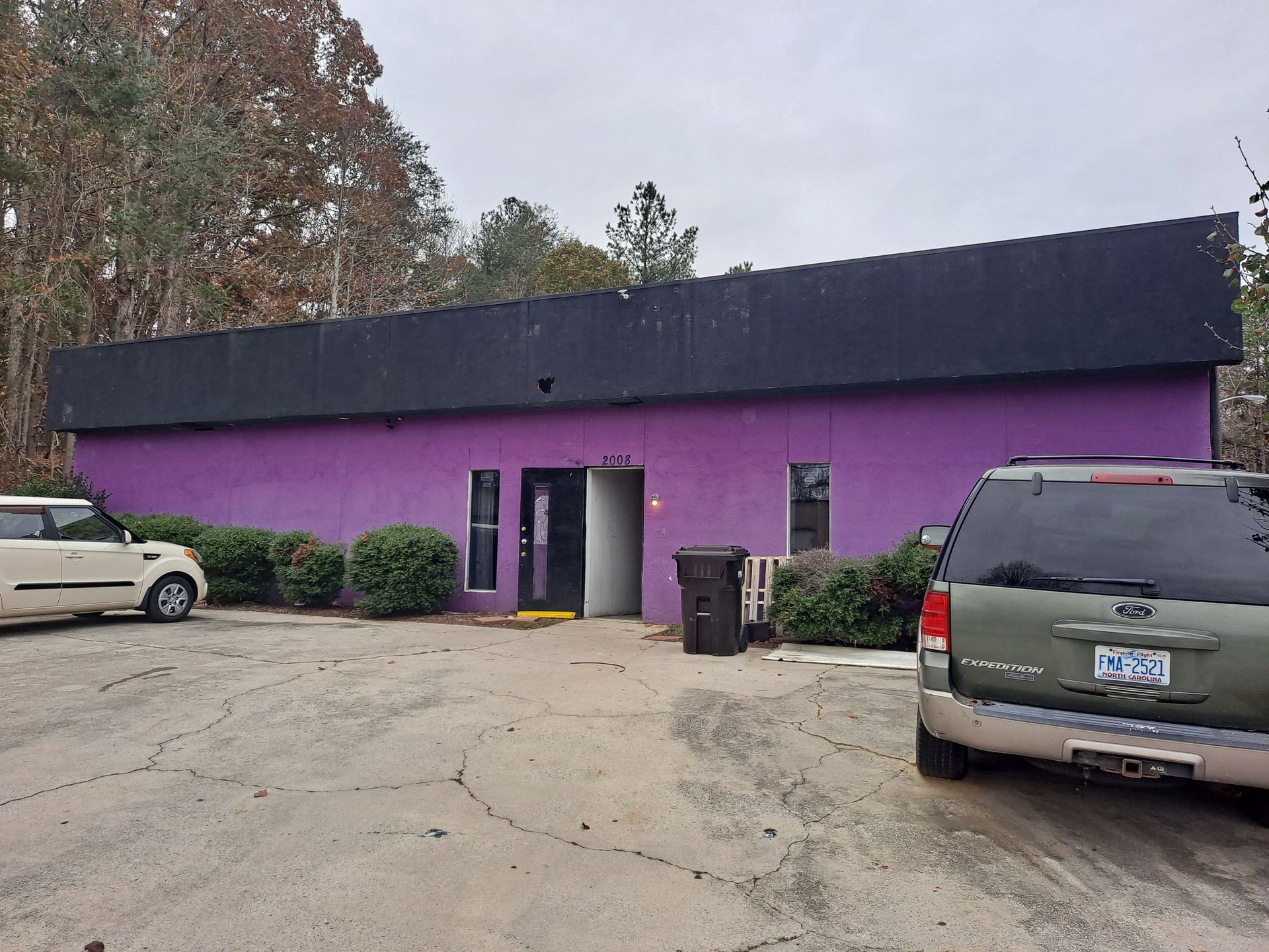 Two cars are parked in front of a purple building.