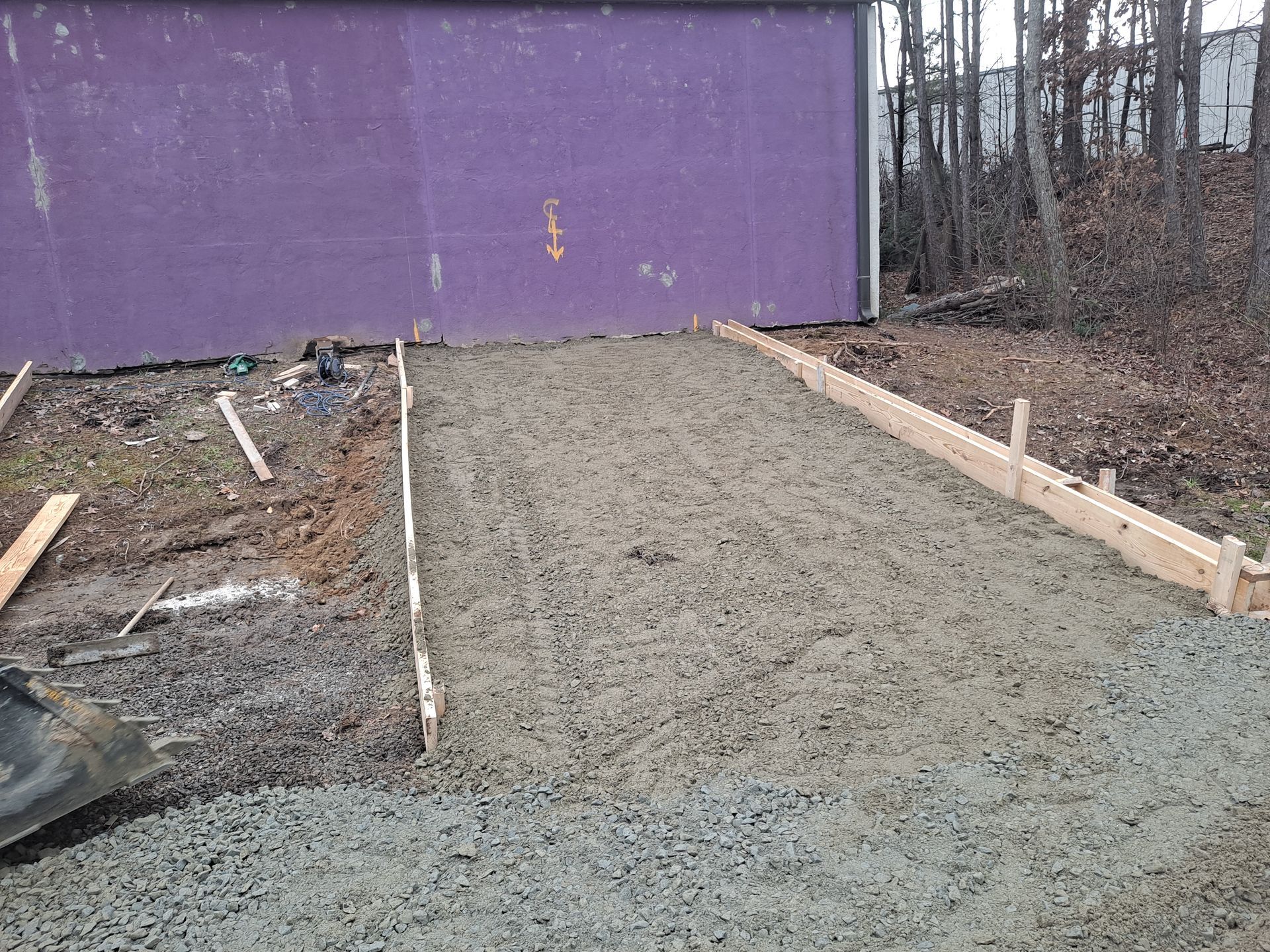 A concrete driveway is being built in front of a purple building.