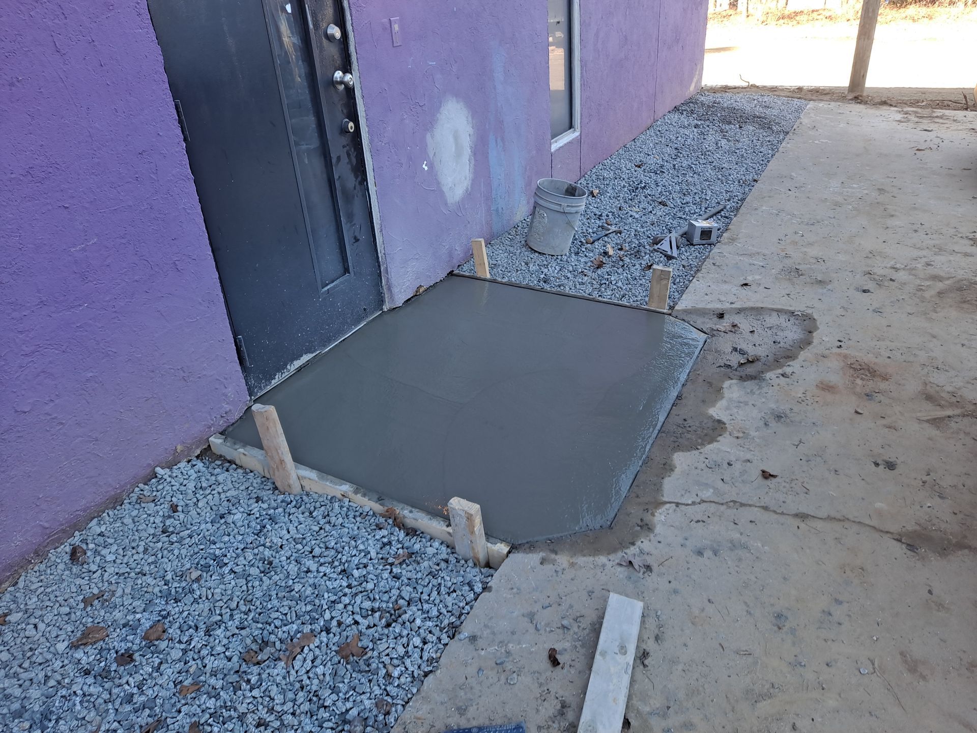 A concrete step is being built in front of a purple building.