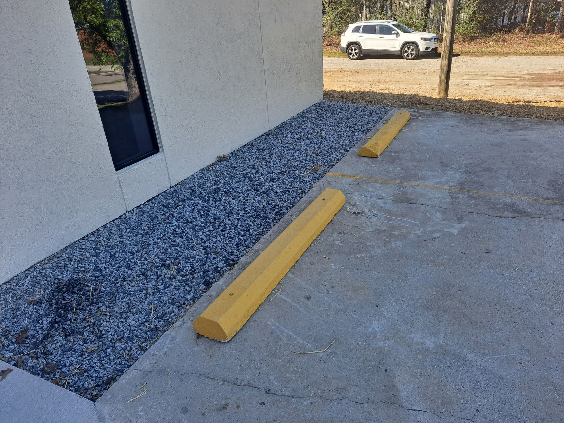 A white car is parked in a parking lot next to a yellow curb.