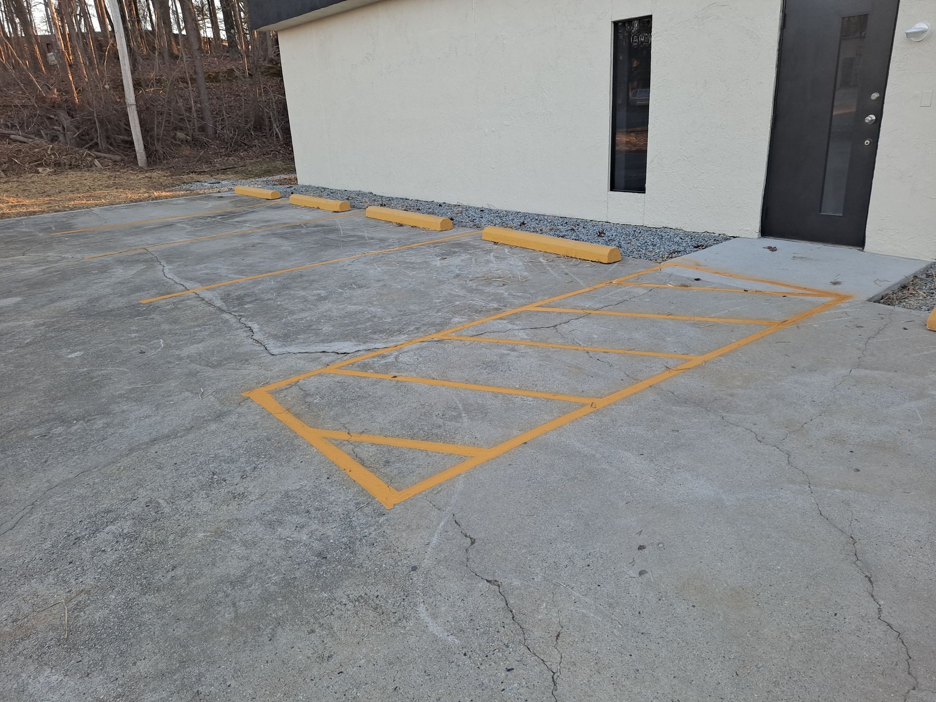 A parking lot with yellow lines painted on it in front of a building.
