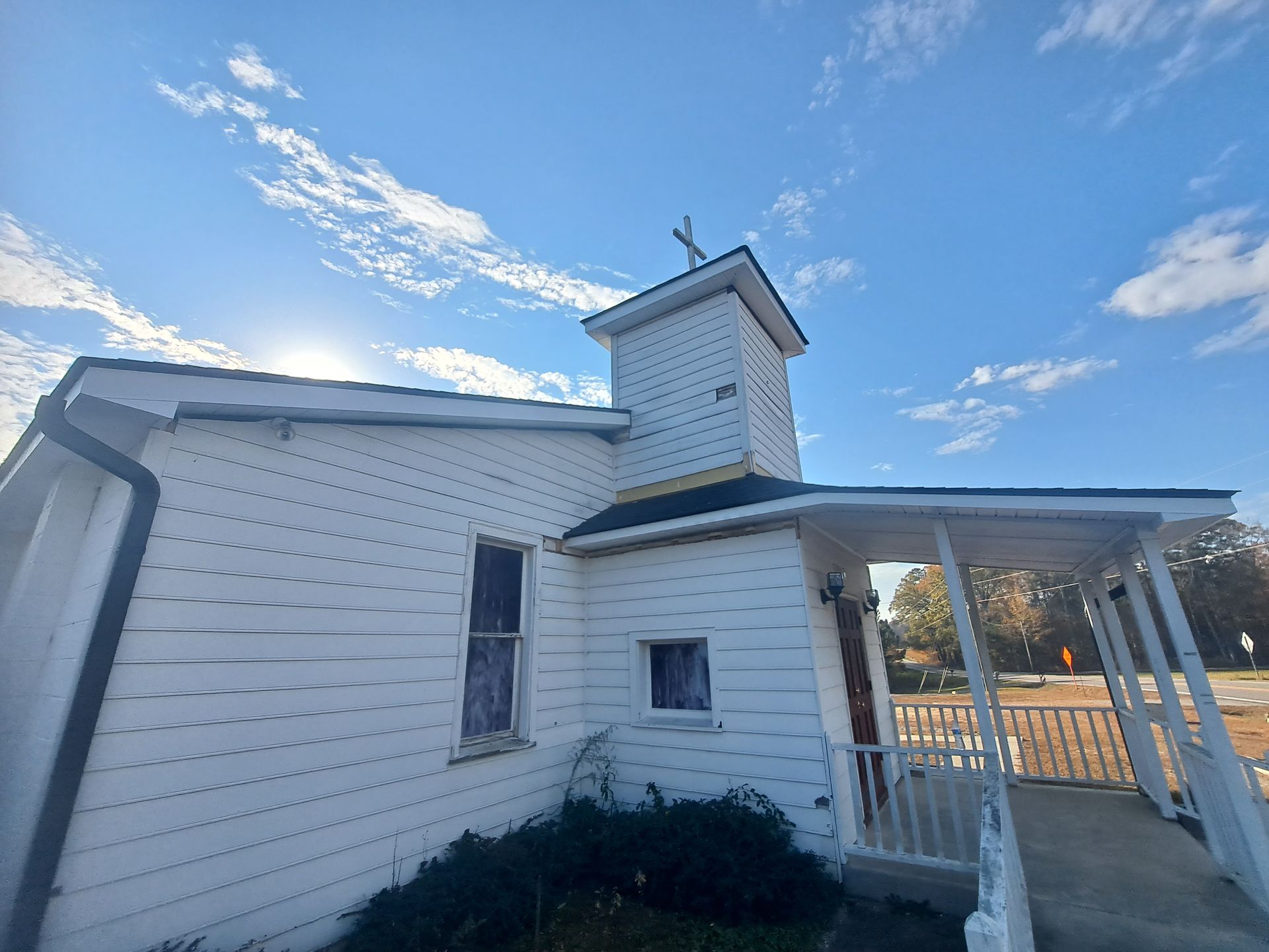A white house with a porch and a tower on top of it.