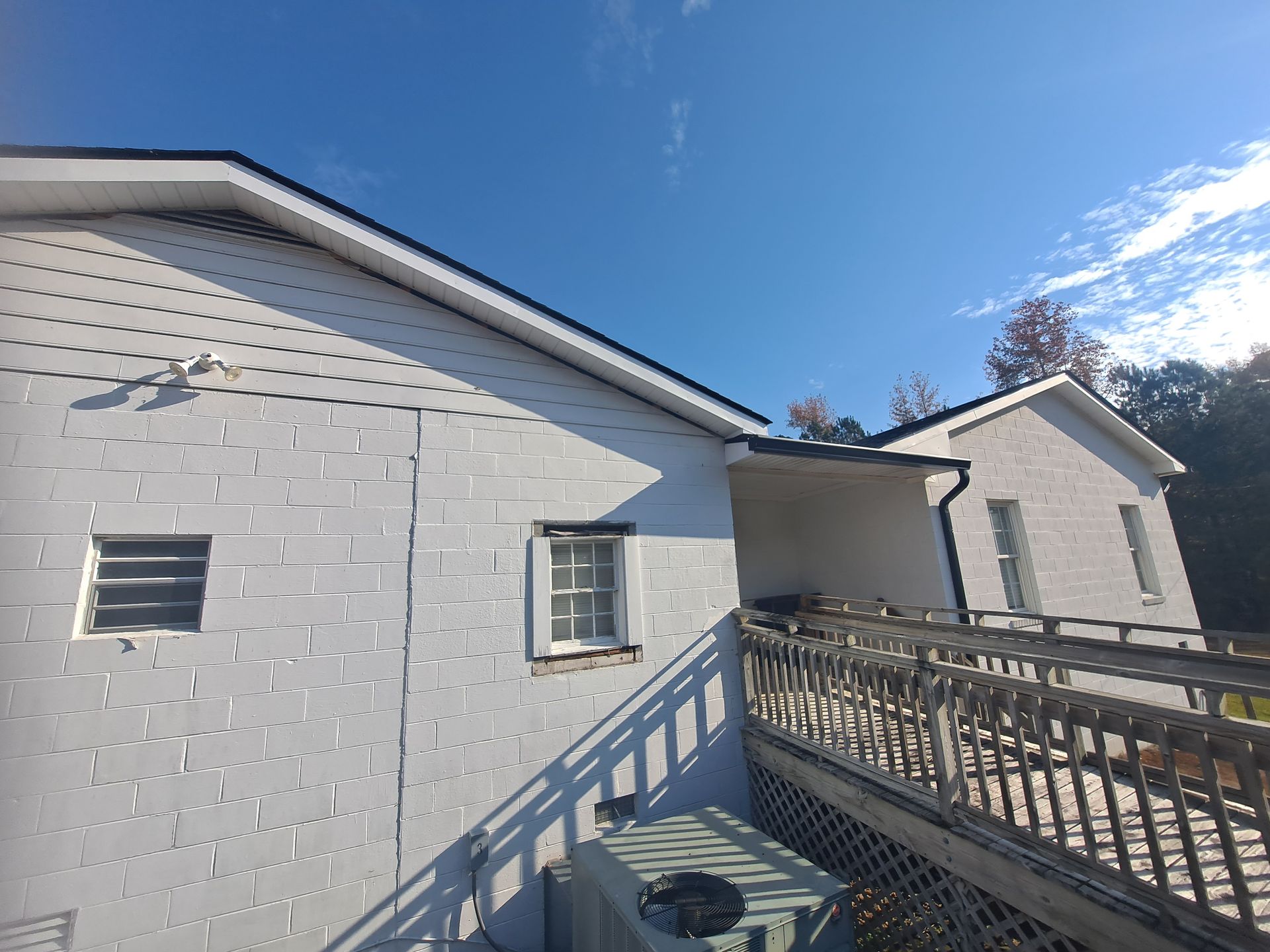 A white brick house with a balcony and a roof