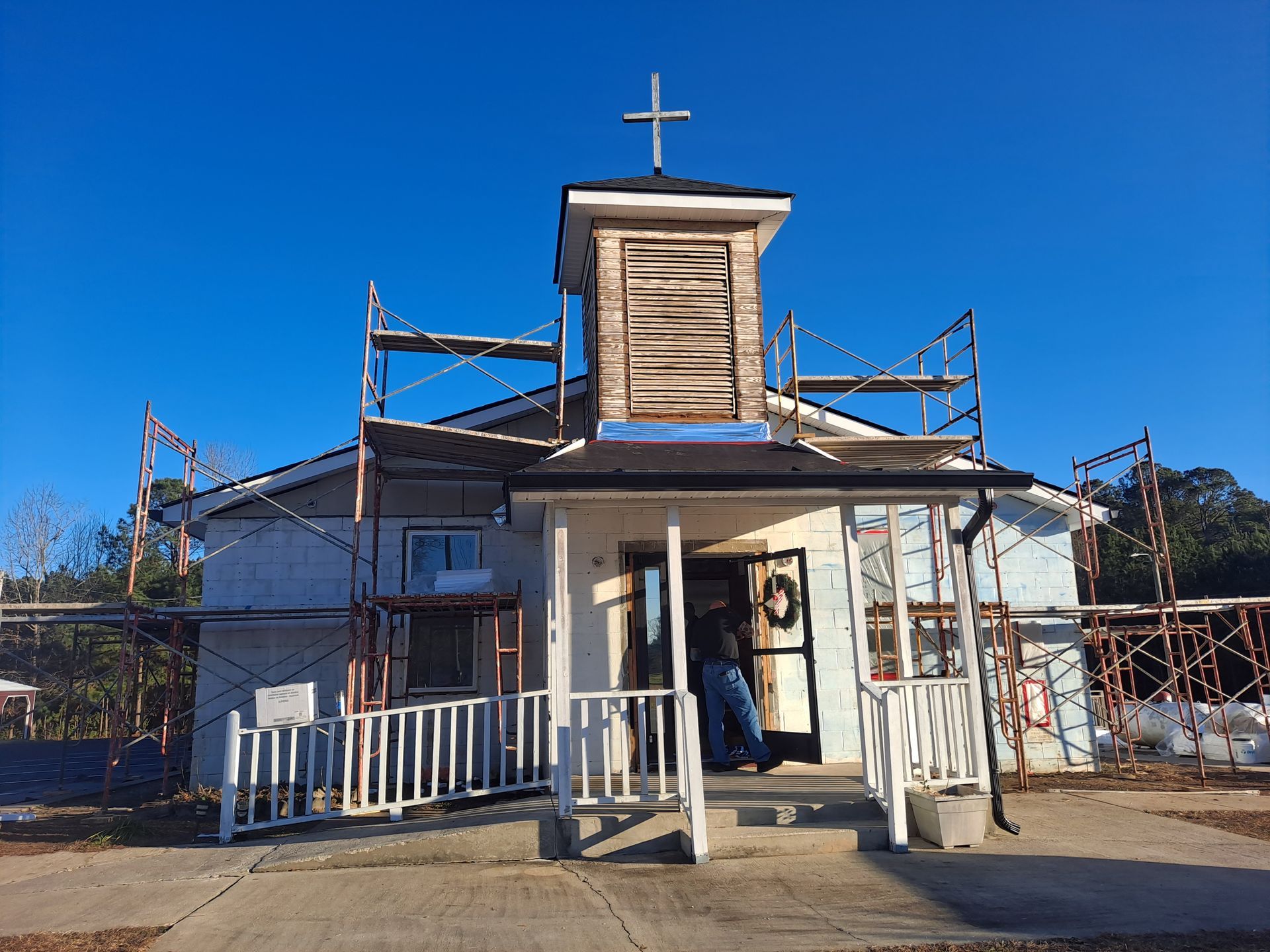 A church under construction with scaffolding around it and a cross on top.