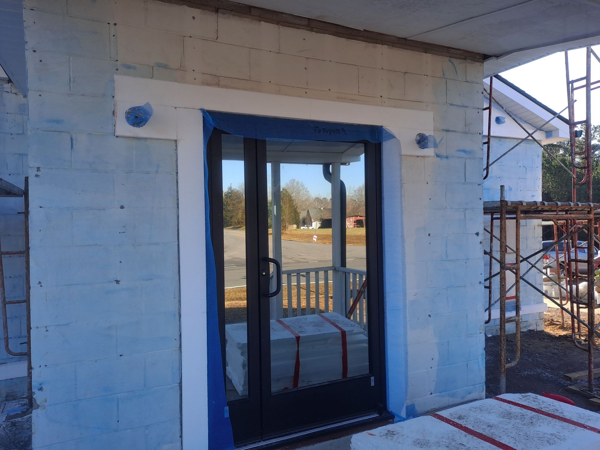 A door is being painted blue and white on a building under construction.