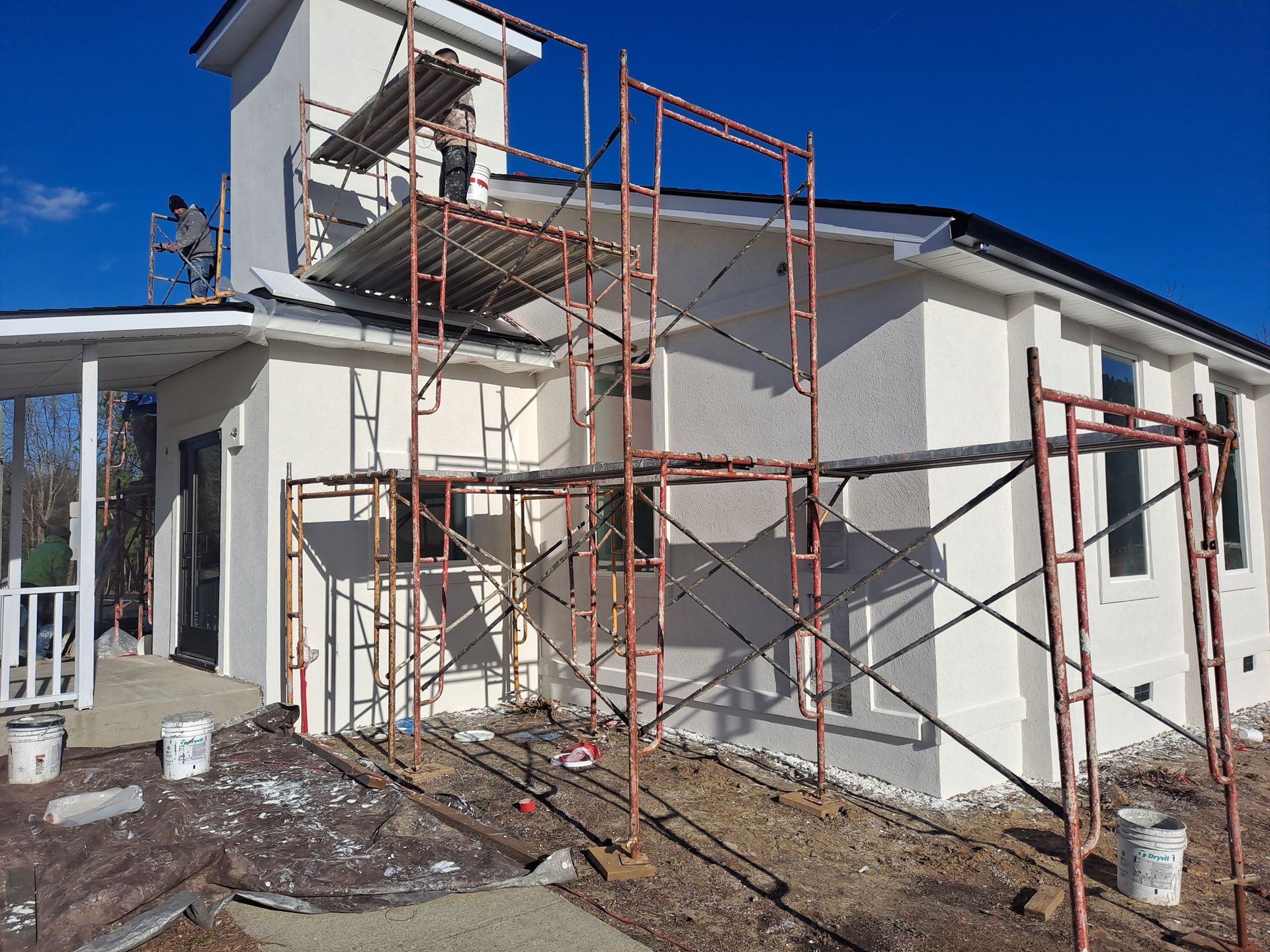 A white house is being painted with scaffolding around it.
