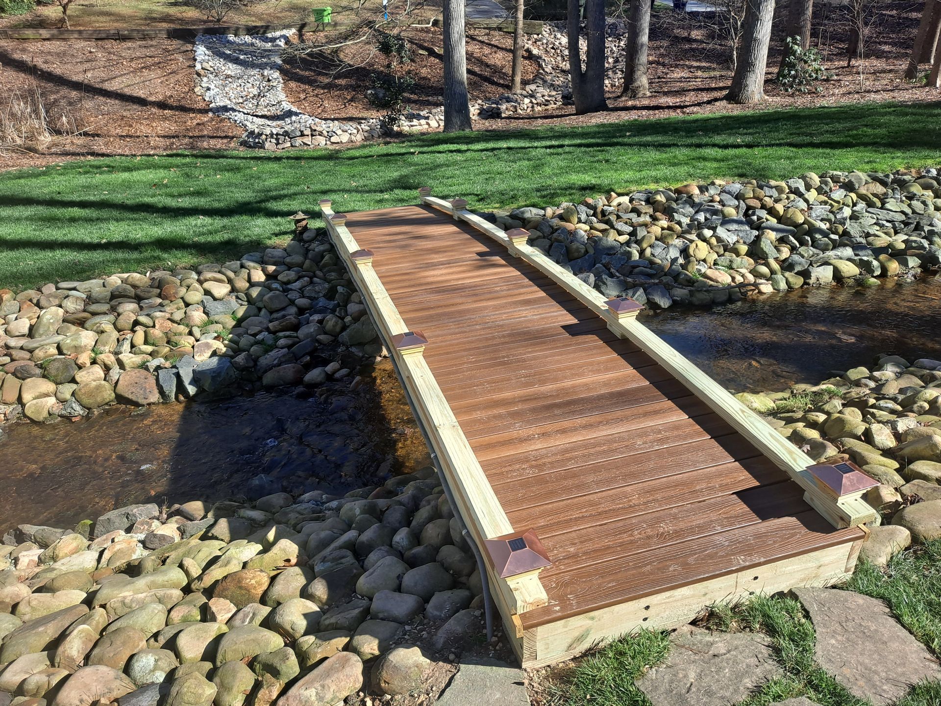 A wooden bridge over a stream in a garden.