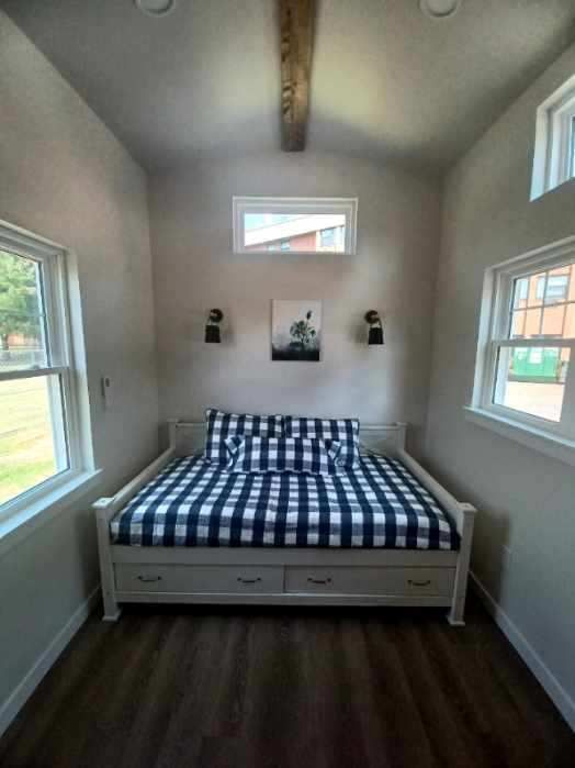 A small bedroom with a bed and two windows.