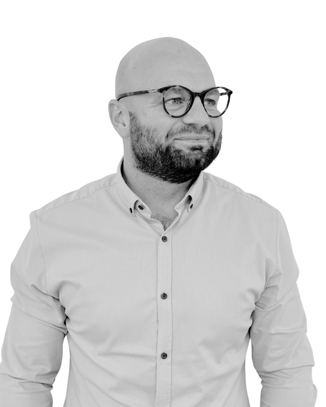 Man with glasses and beard, wearing a button-down shirt, looking to the side with a slight smile.