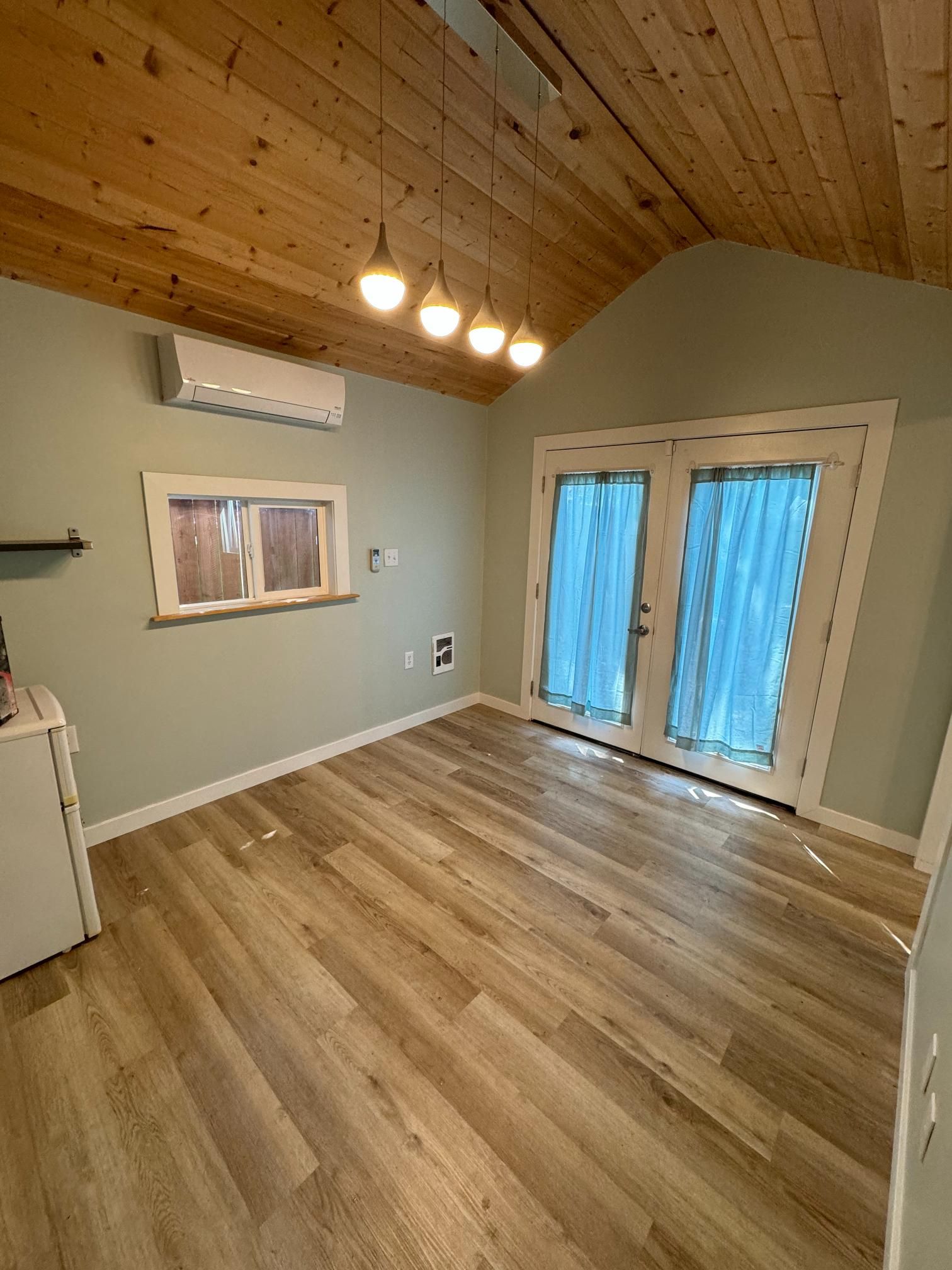 Room with wood ceiling, light green walls, wood floors, and French doors.