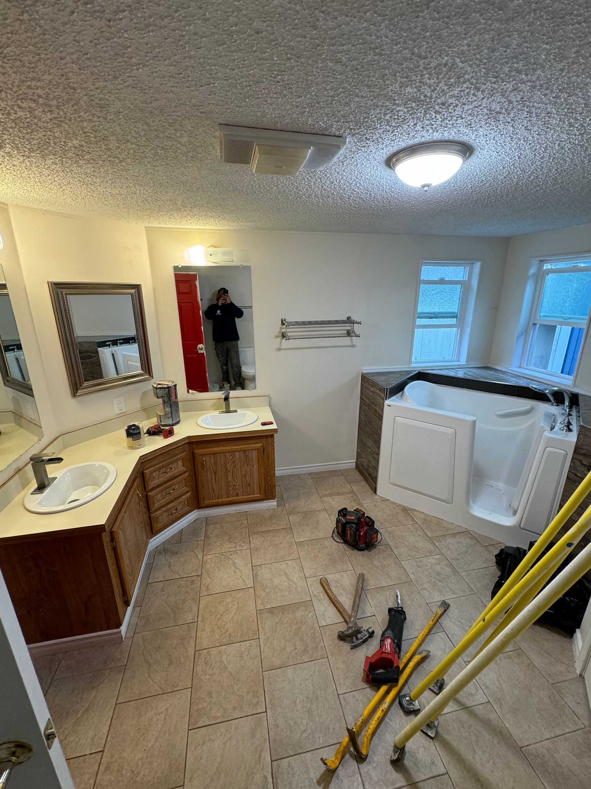 Bathroom renovation in progress with a walk-in tub and vanity. Tools on the floor.