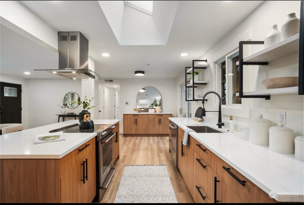 Modern kitchen with wood cabinets, white countertops, and stainless steel appliances.