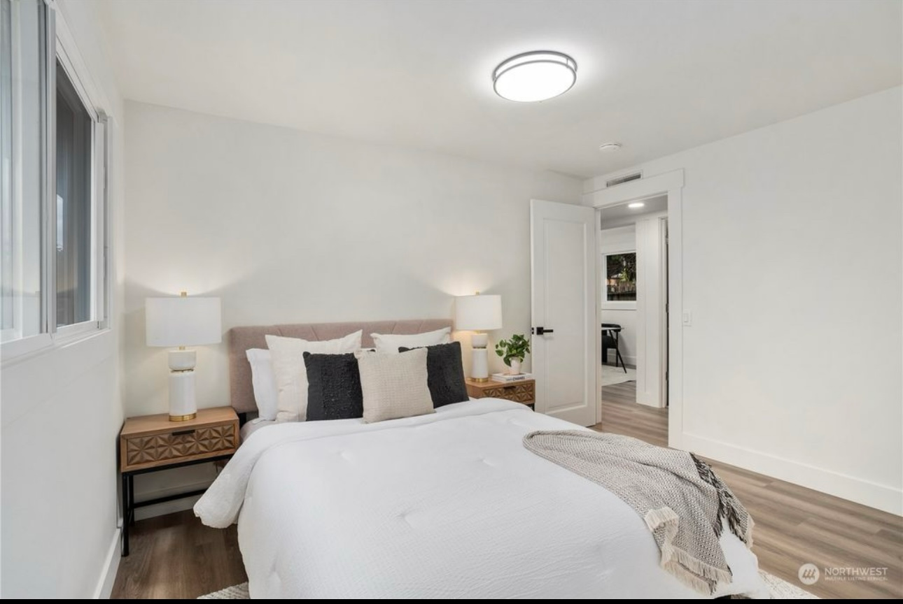 Bedroom with white walls, bed, two nightstands, and a doorway to a hallway.
